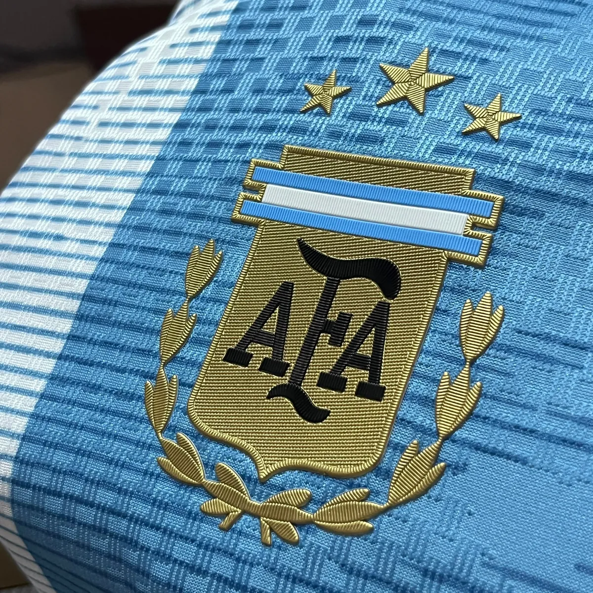 Embroidered gold AFA crest with three stars on the celeste knit