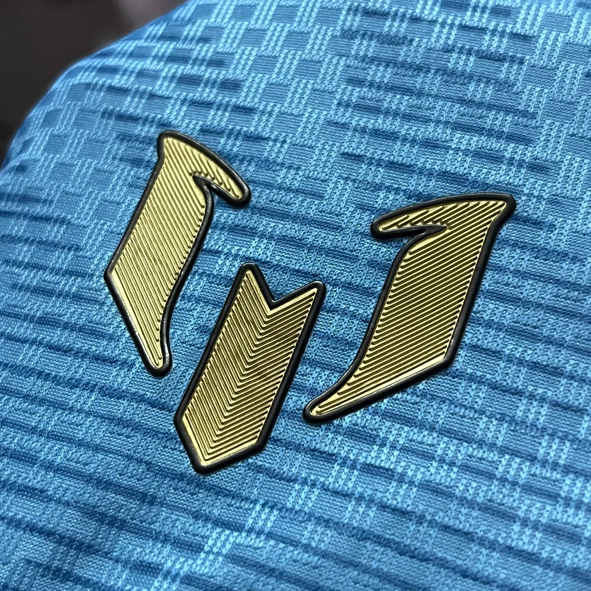 Gold Messi emblem with black keyline on the chest