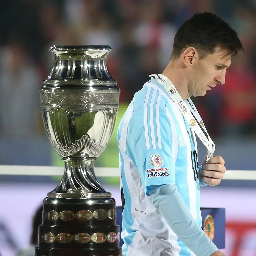 Messi walking past the Copa América trophy with his runner-up medal in 2015