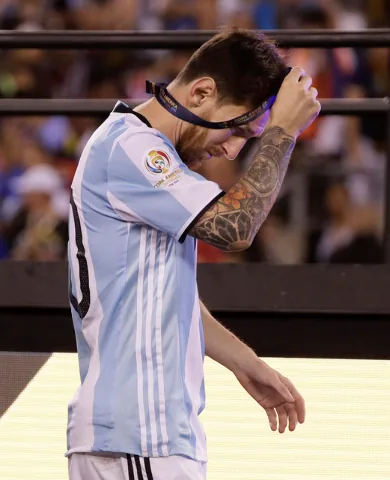 Messi lowering his runner-up medal from his head after the 2016 Copa América final