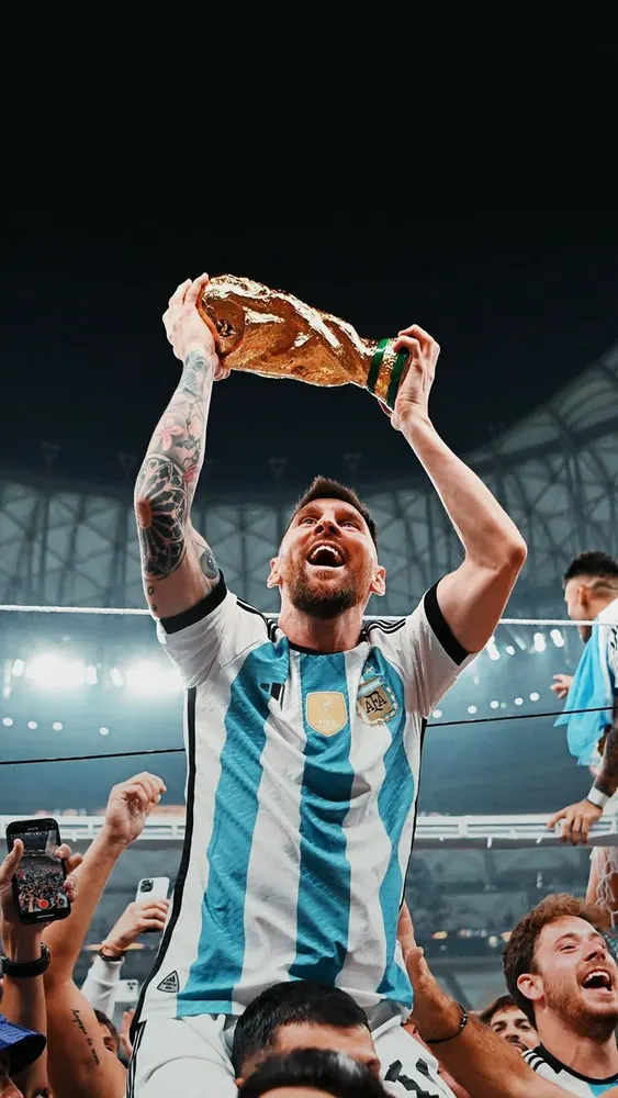 Messi lifted on shoulders holding the World Cup trophy above his head in Lusail